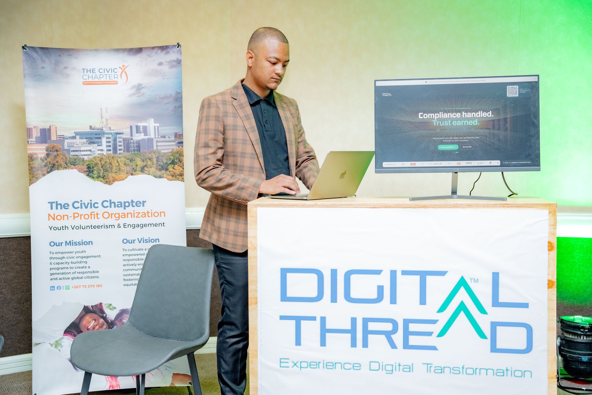 Maverick Kabelo at the Digital Thread booth, working on a laptop beside a Civic Chapter flyer