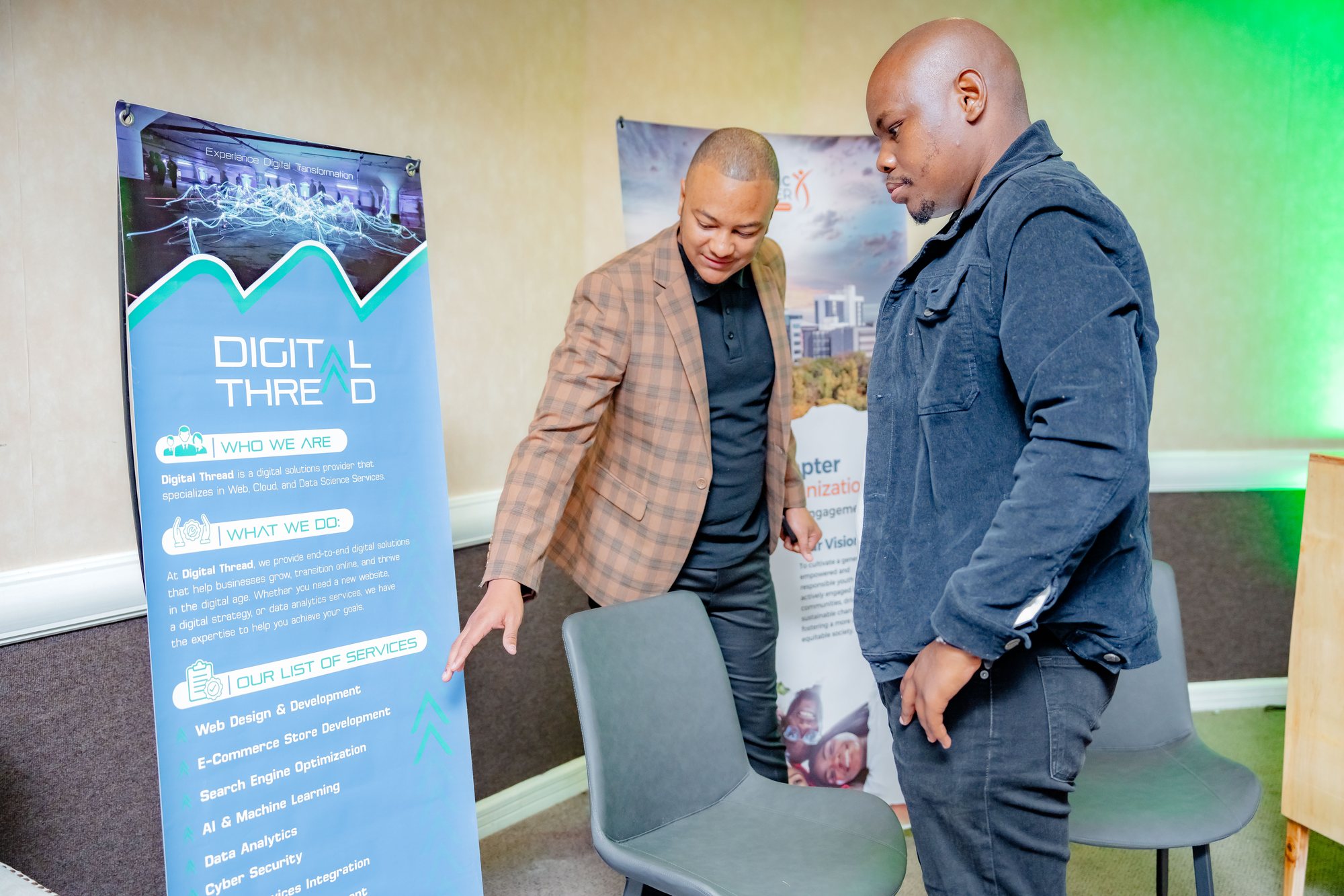 Maverick Kabelo talking with an attendee beside the Digital Thread banner